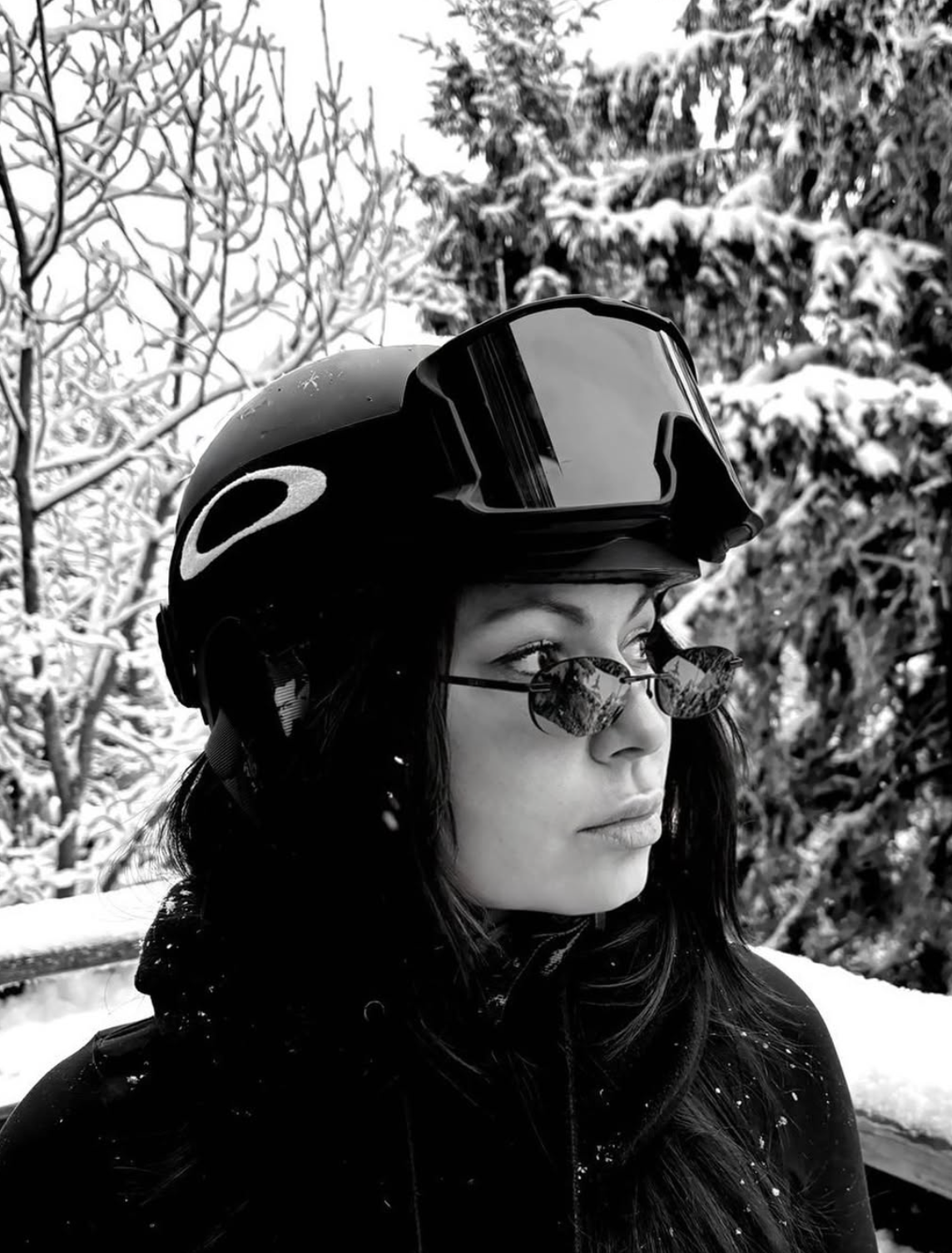 Person wearing a helmet and sunglasses with a snowy background
